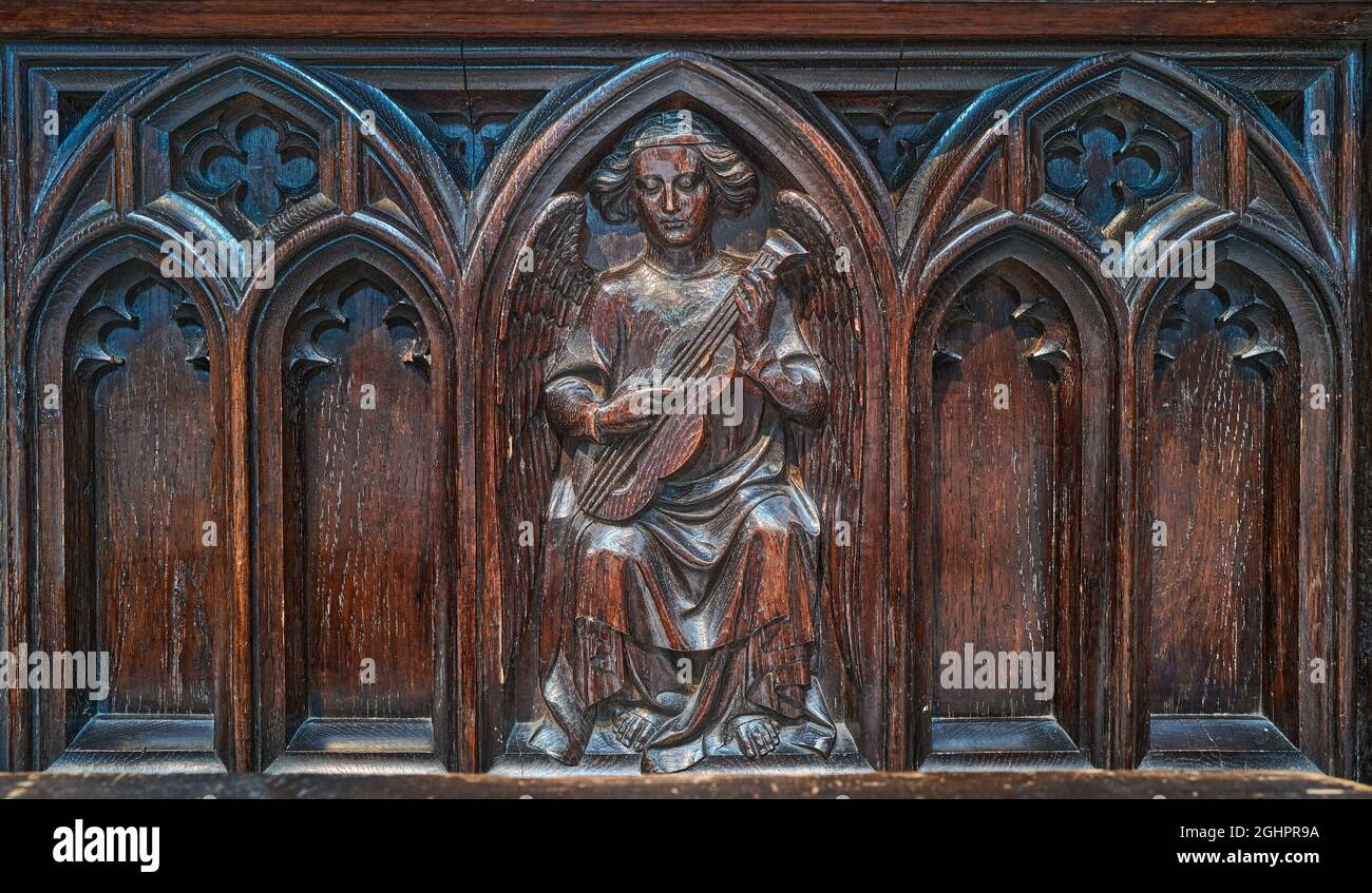 Carved wooden panel (of an angel with a musical instrument) on a stall in the choir of the cathedral at Lincoln, England. Stock Photo