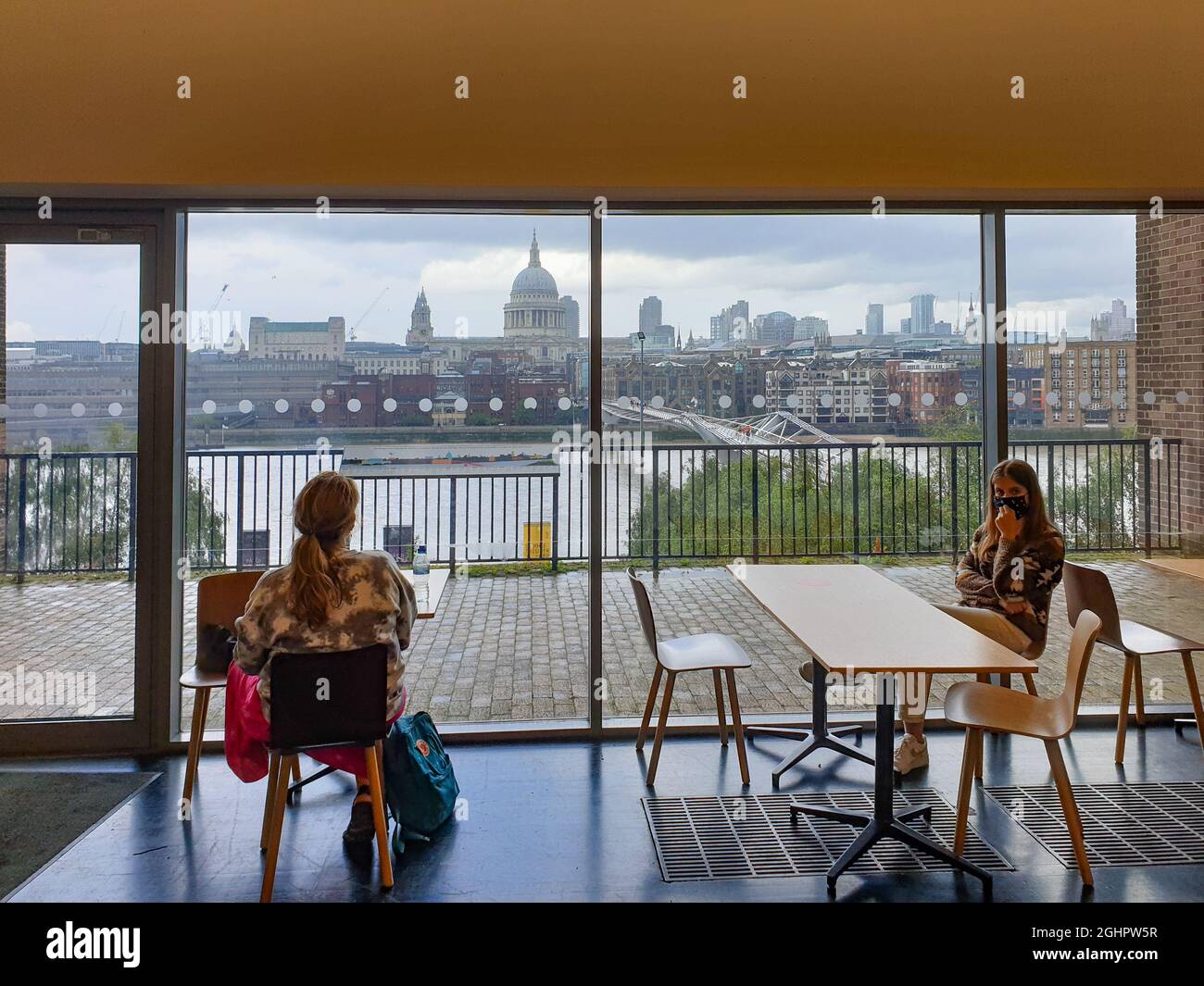 London, United Kingdom - July 30, 2021: Two women relax at the Cafe of Tate Modern Gallery overlooking St Paul's Cathedral Stock Photo