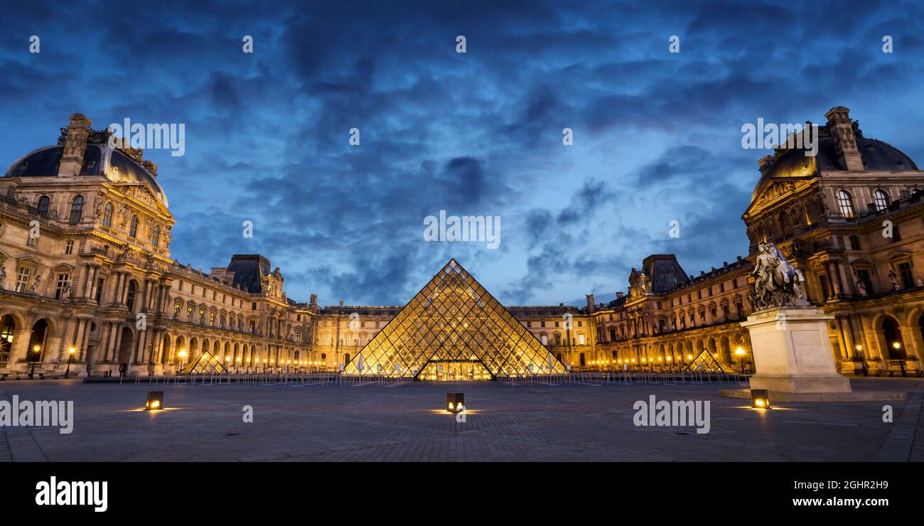 Panorama of the museum and pyramid of Le Louvre illuminated at night in Paris France Stock Photo