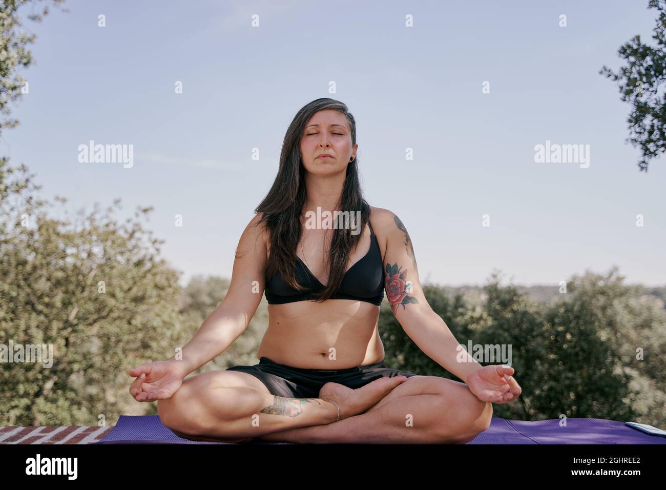 Woman meditating in yoga posture outdoors. Concept of meditation and leisure activities. Stock Photo