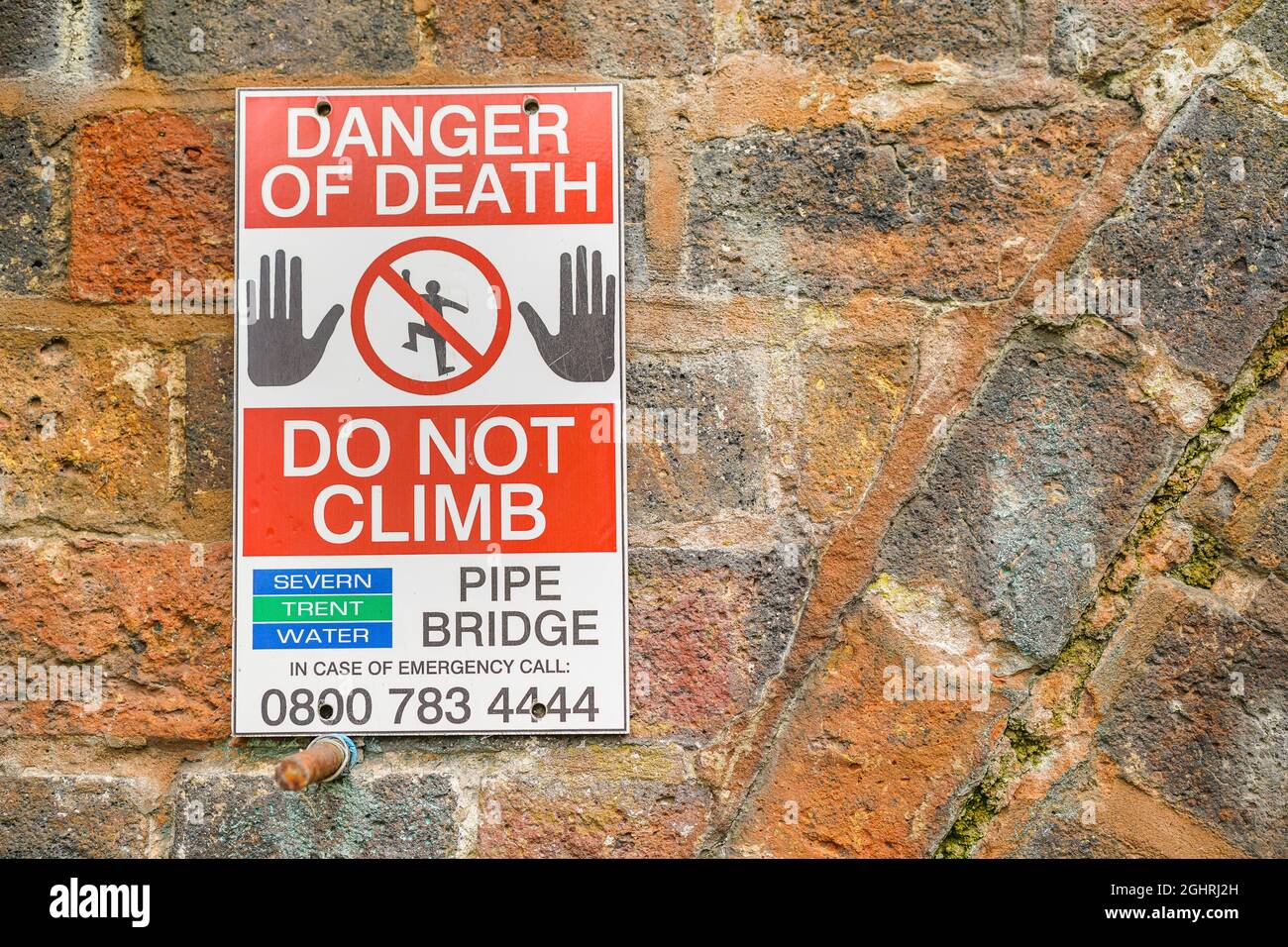Severn Trent Water 'Danger of Death, Do Not Climb' warning sign in place on brick pipe bridge over a UK canal. Stock Photo