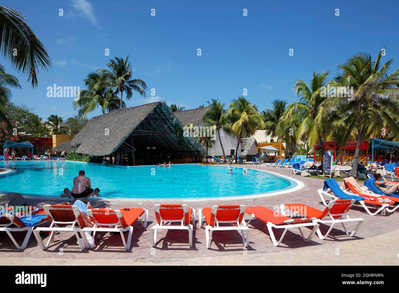 Pool, sun loungers, pool bar with palm leaf roof, coconut trees (Cocos nusifera) Hotel Brisas, Playa St. Lucia, Camagueey Province, Caribbean, Cuba Stock Photo