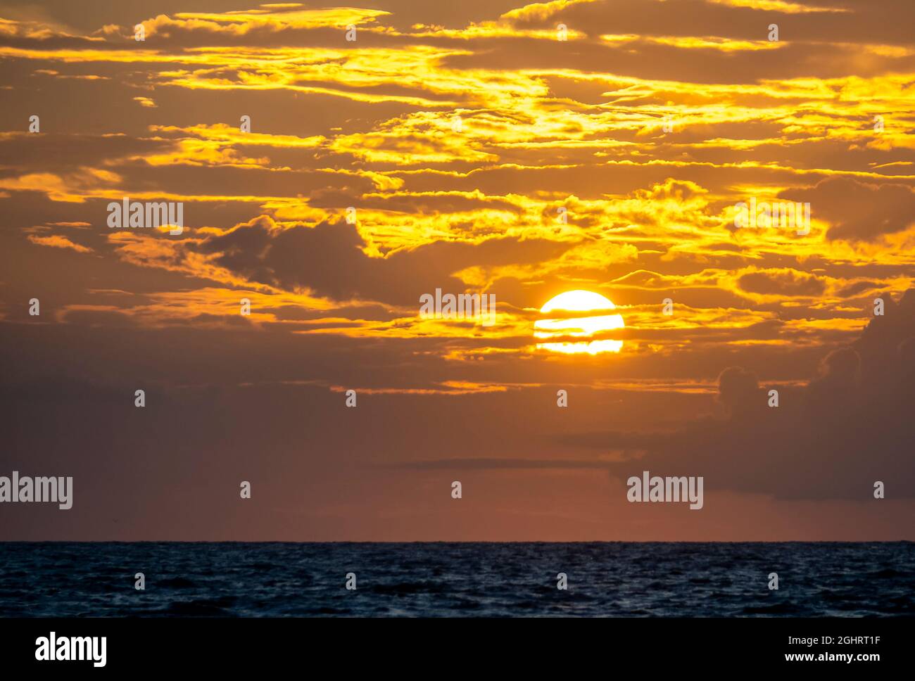 Orange yellow sky with clouds and sun near sunset over the Gulf of Mexico in Southwestern Florida USA Stock Photo