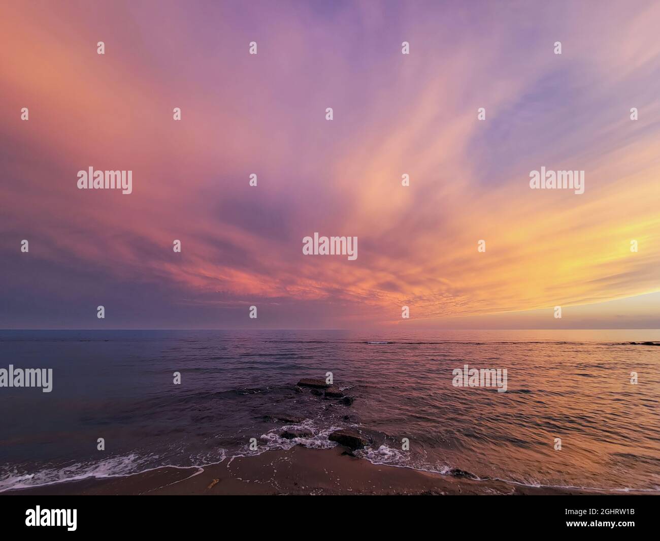 Multicolored sky, spectacular sunset over the sea with waves on the