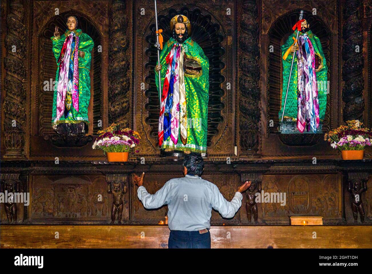Shaman talking to wooden figures of the saints, dressed in traditional traditional costume, colonial-era Iglesia Parroquial Santiago Apostol of 1566 Stock Photo