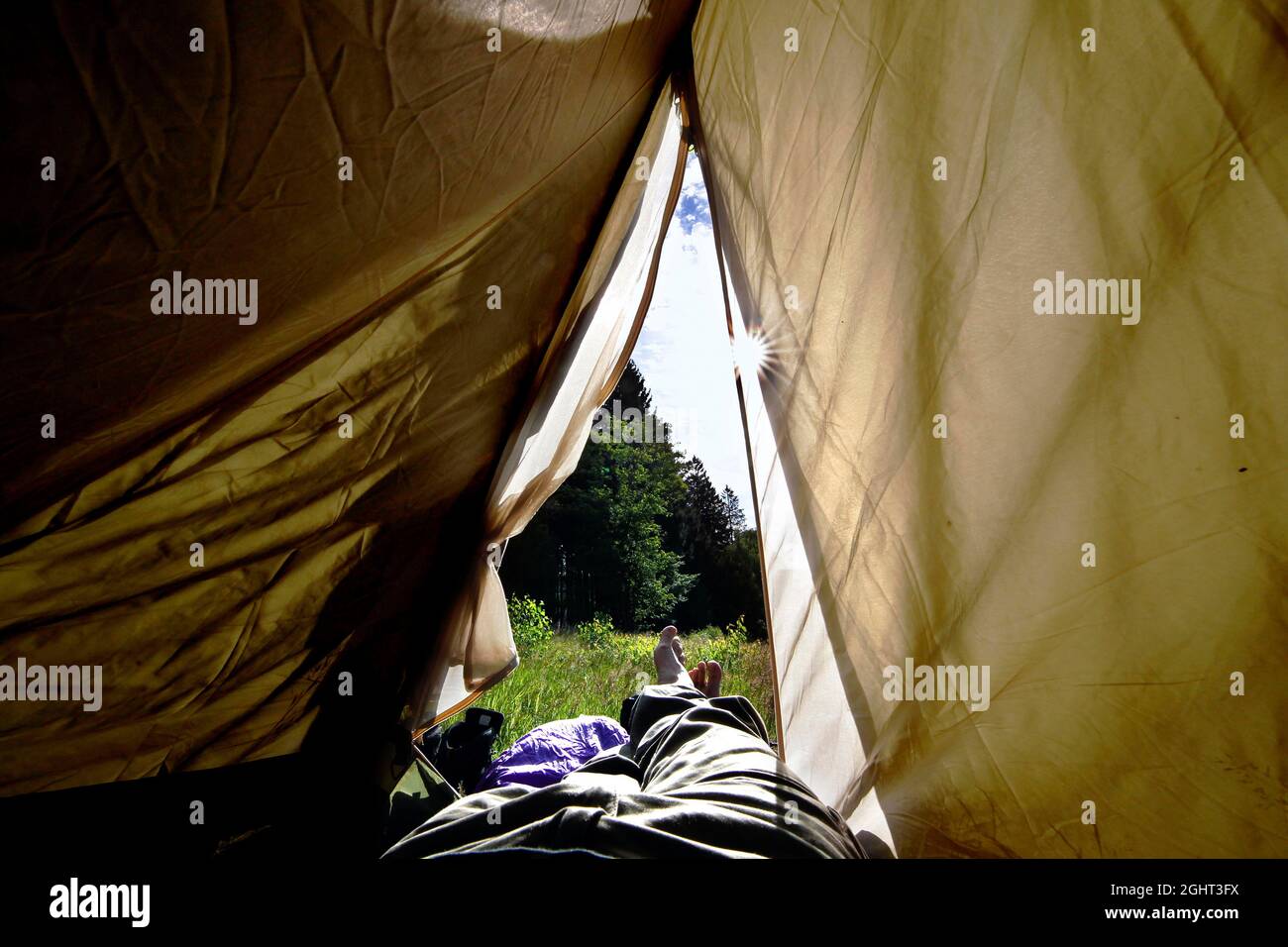 Legs peeping out of tent, hiker camping, column trail, perforated plate trail, hiking trail through forest, Green Belt, border trail, former Stock Photo