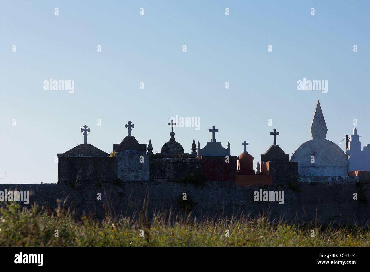 Silhouettes at sunset of crosses in a cemetery in Galicia, Spain. Crosses and symbology in a cemetery. Stock Photo
