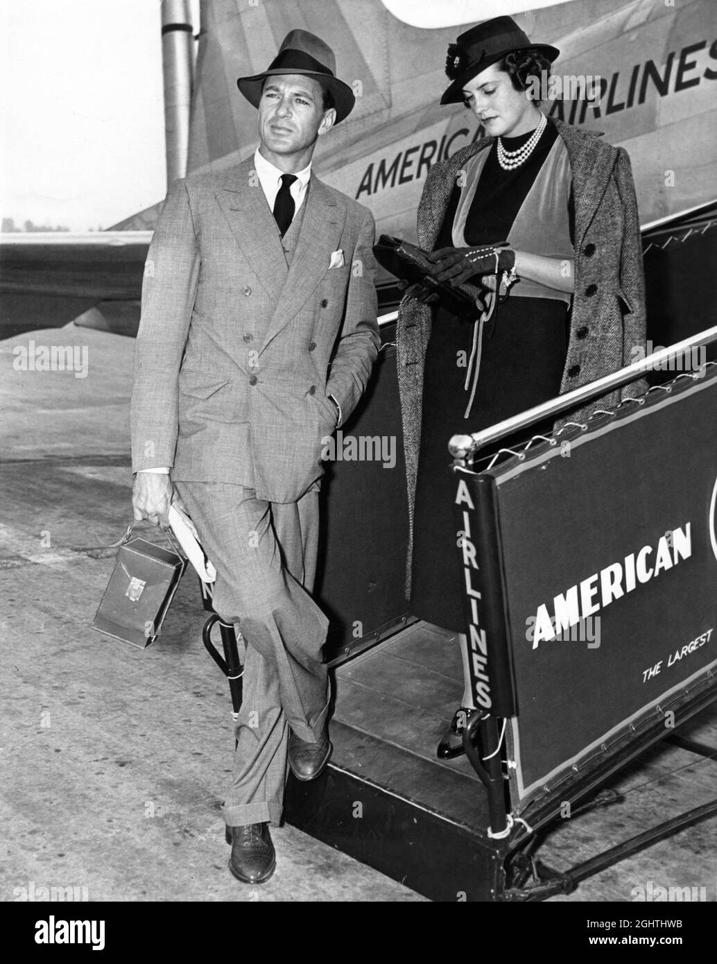 GARY COOPER and His Wife VERONICA BALFE aka SANDRA SHAW aka ROCKY COOPER circa 1938 next to gangway to an American Airlines Aircraft Stock Photo