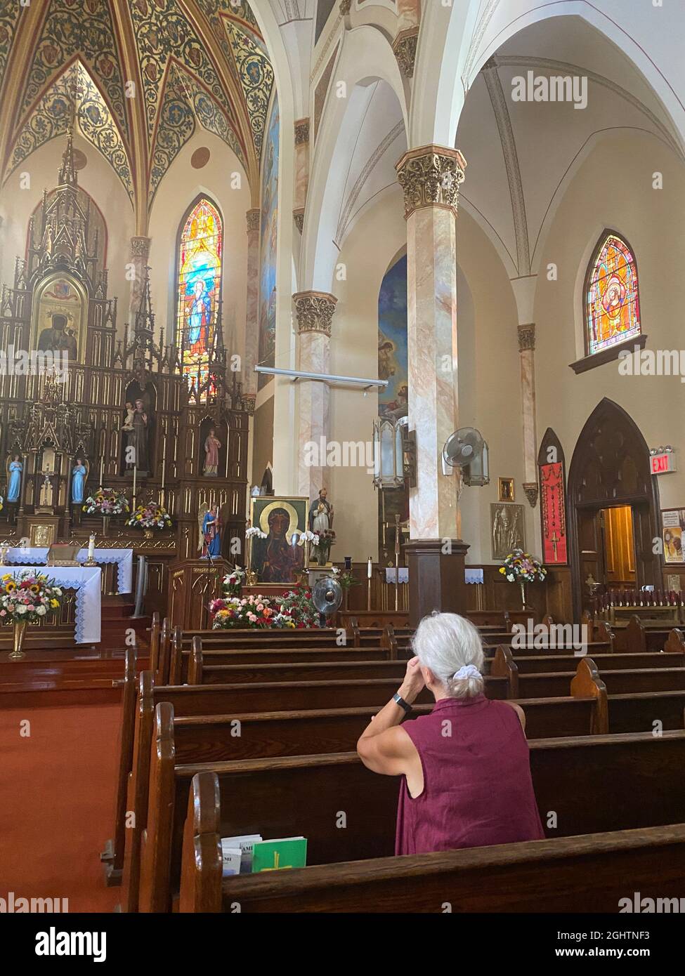 Woman deep in prayer at a Catholic Church in Sunset Park, Brooklyn, New York. Church is empty due to the Covid-19 pandemic. Stock Photo