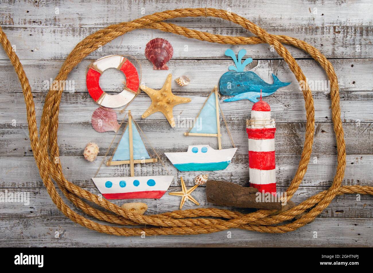 Cute set of kids handcrafted boats, fish, nautical attributes and more on rough vintage wooden background top view Stock Photo