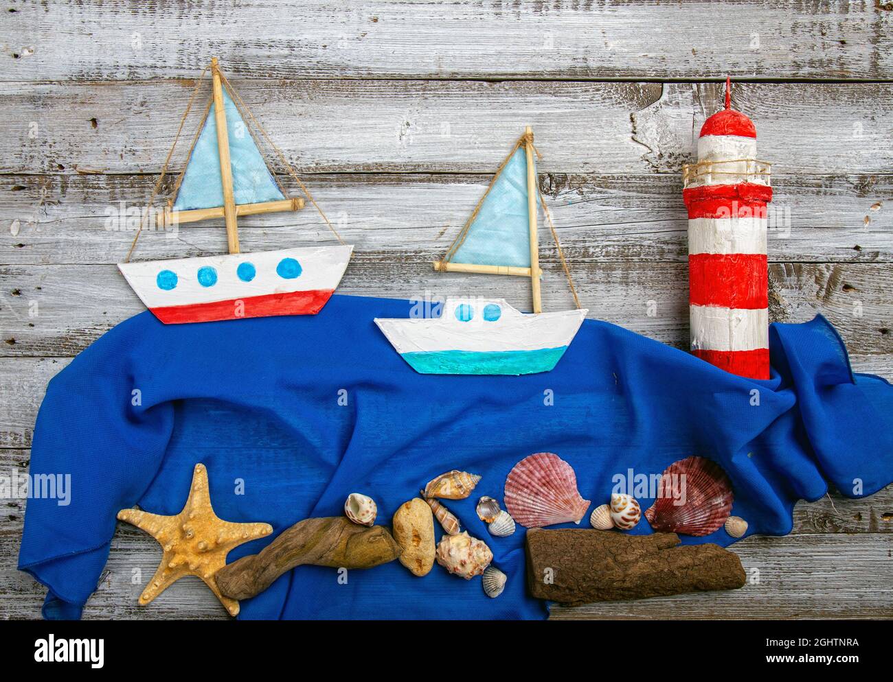 Cute set of kids handcrafted boats, fish, nautical attributes and more on rough vintage wooden background top view Stock Photo