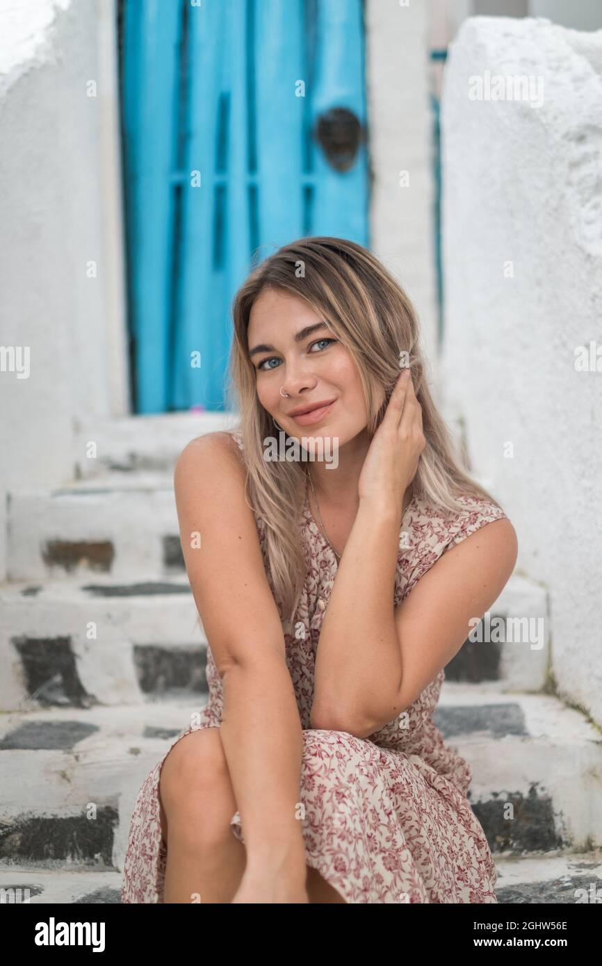 Close-up portrait of pretty caucasian blond girl with attractive blue eyes in casual dress. Sitting outdoors and smiling. Stock Photo