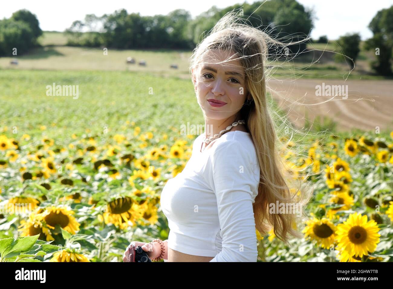 Portrait of a beautiful teenage girl standing in a sunflower field ...