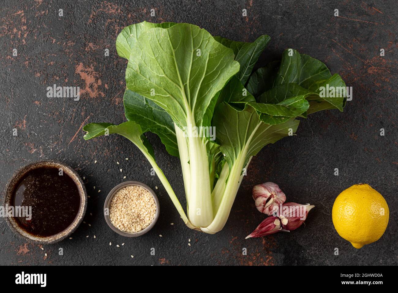 Asian food cooking concept. Fresh harvested organic bok choy chinese cabbage with ingredients on black background. Top view Stock Photo