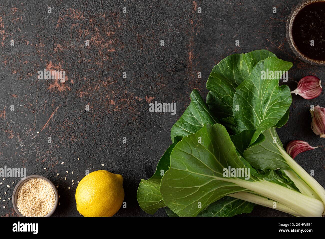 Fresh harvested organic bok choy chinese cabbage with ingredients for cooking asian food on black background. Top view with copy space Stock Photo