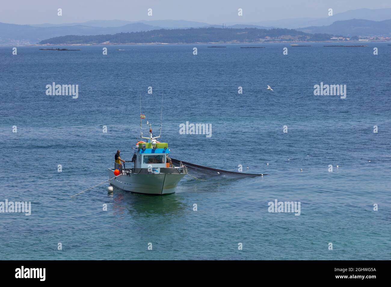Fishing boat, collecting nets full of fish. fishing near the coast ...