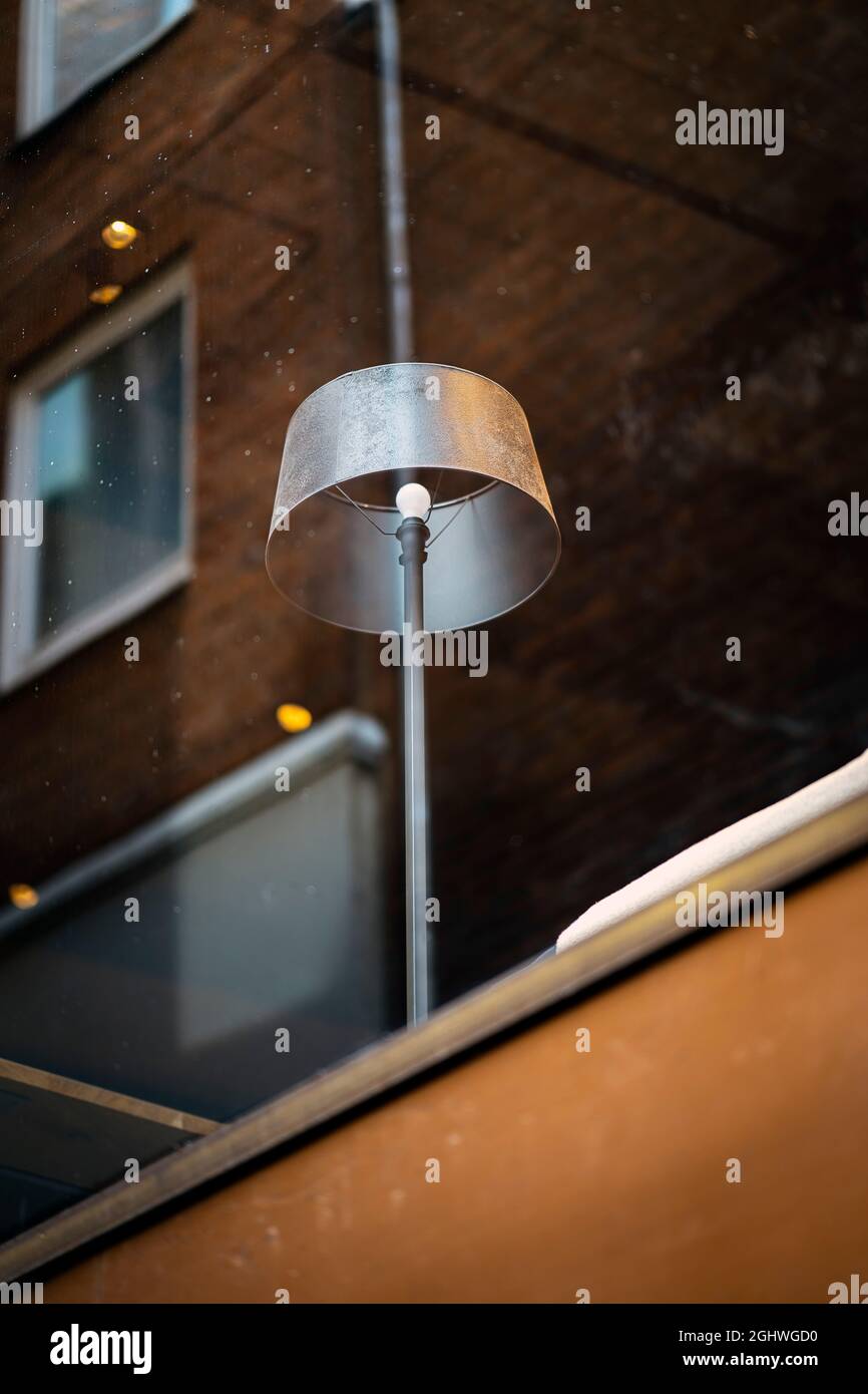 Floor lamp shining through a relecting coffeehouse window Stock Photo