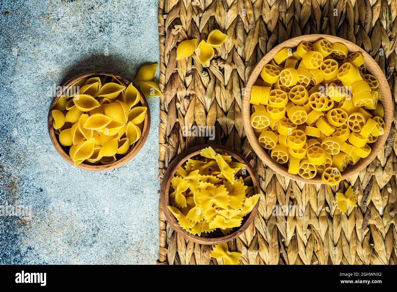 Bowls of raw farfalle, ruote and Conchiglie pasta shells on a table Stock Photo