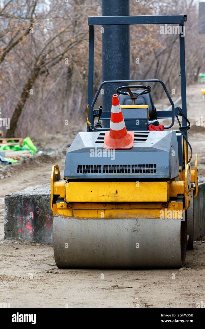 The compact road roller stands on a construction site with a leveled