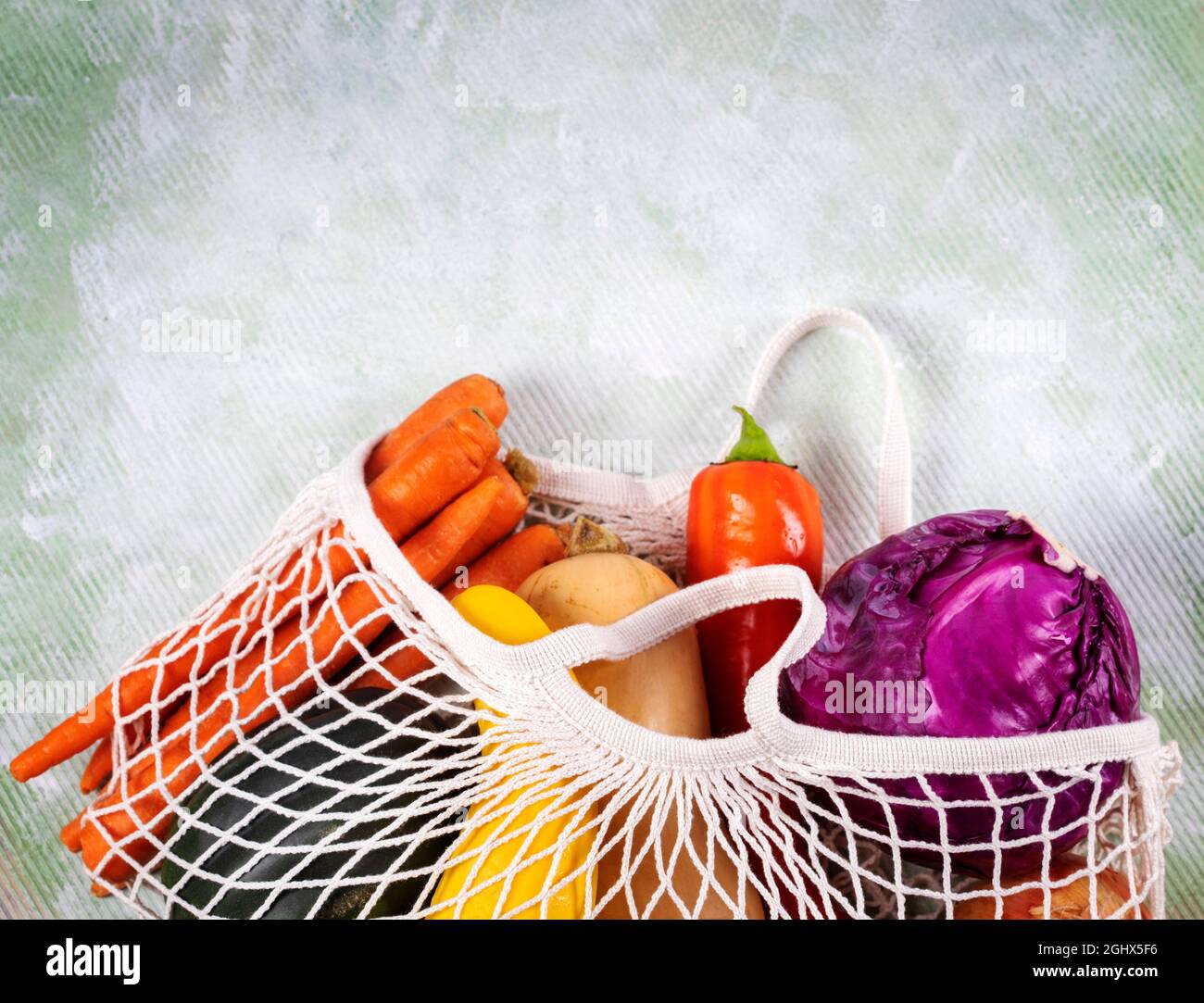 Reusable mesh bag with assorted fruit and vegetables on a table Stock Photo