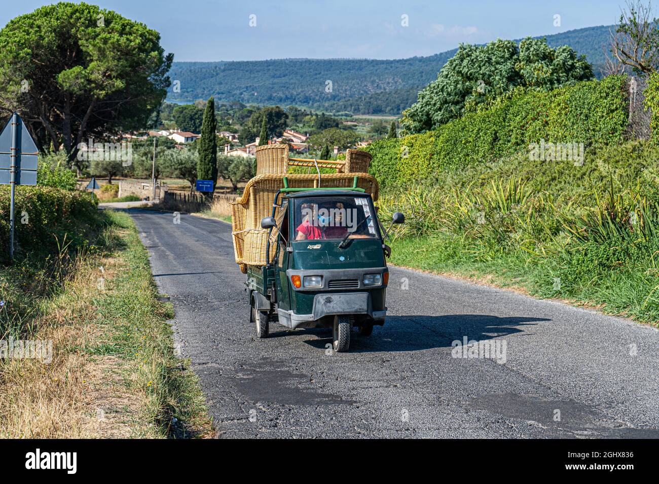A Piaggio Ape 50 three wheeled van in Green Sherwood  transporting furniture in Italian countryside Stock Photo