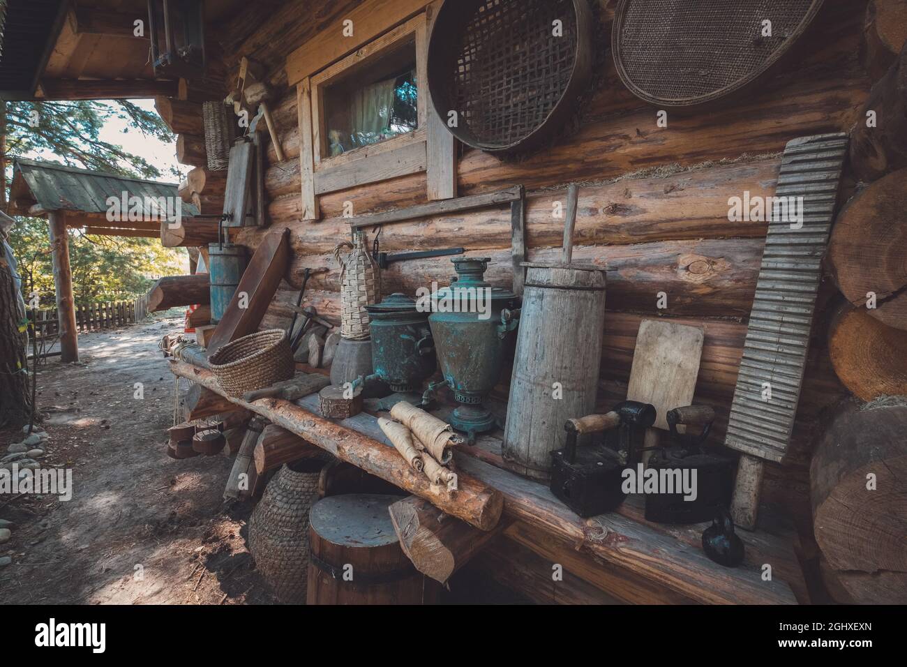 Retro houseware on a wooden bench near wooden wall. Antique household items of peasant. Stock Photo