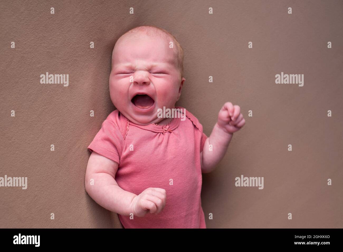 Little crying newborn baby on a brown blanket Stock Photo