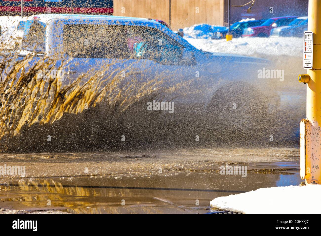 Vehicles driving through standing water from snowmelt creating muddy spray. Stock Photo