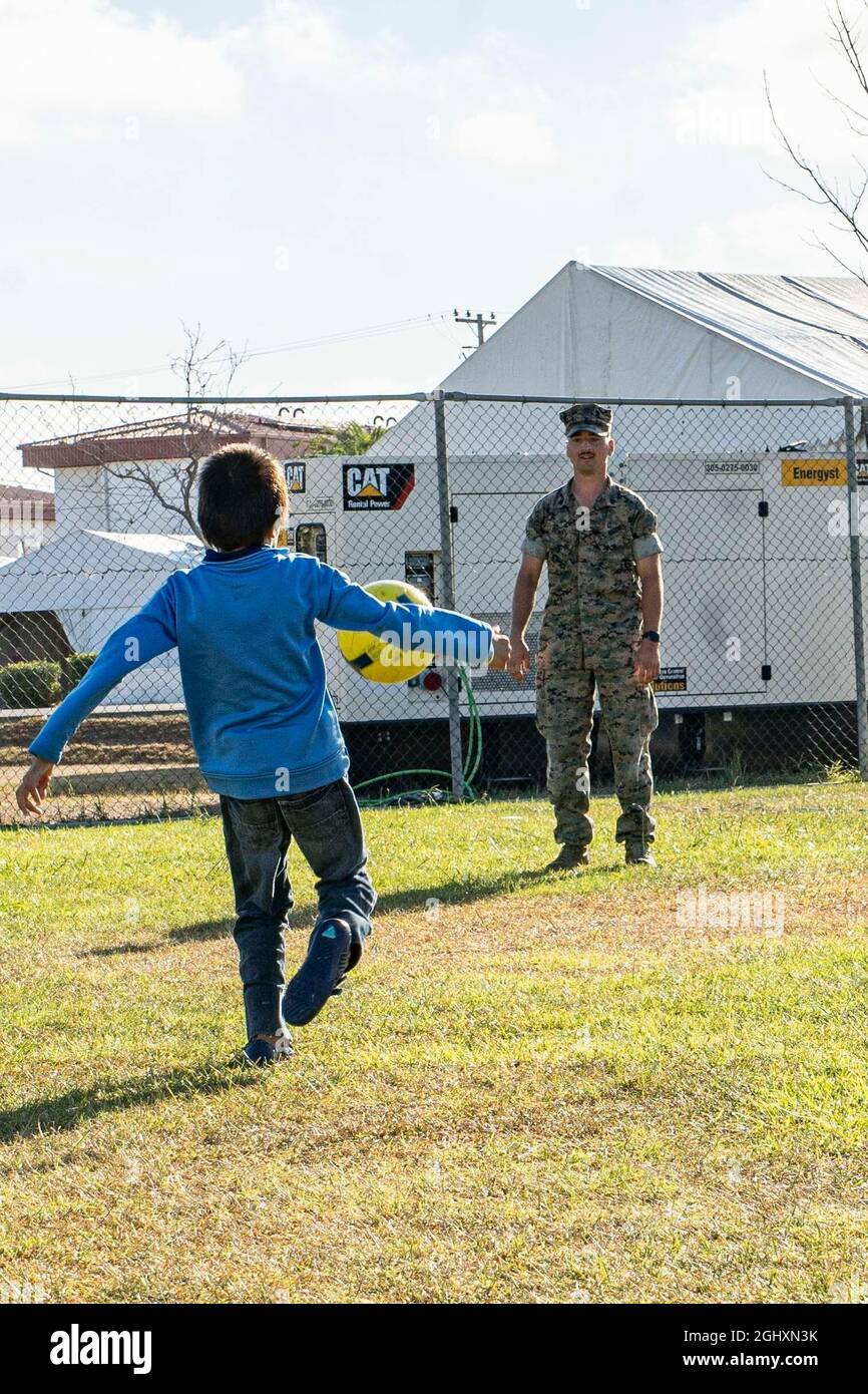 NAVAL STATION ROTA, Spain (Sept. 3, 2021) A U.S. Marine kicks a ball with an evacuee from Afghanistan at Naval Station Rota, Spain, Sept. 3, 2021. NAVSTA Rota is supporting the Department of State mission to facilitate the safe departure and relocation of U.S. citizens, Special Immigration Visa recipients, and vulnerable populations from Afghanistan. (U.S. Marine Corps photo by Sgt. Claudia Nix) Stock Photo