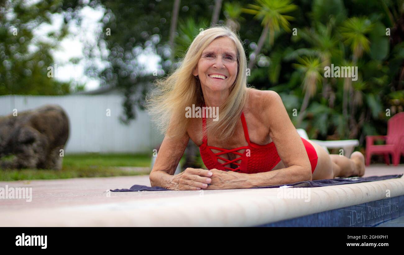 Healthy Senior Woman Laying On The Poolside Floor Stock Photo