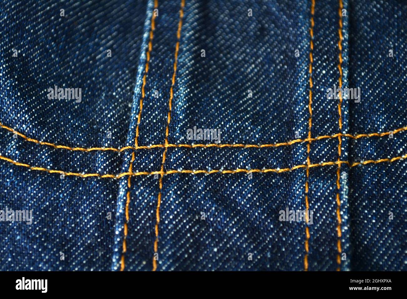 Yellow sewing on blue jeans from closeup. Studio shot at blue clothes texture from close. Stock Photo