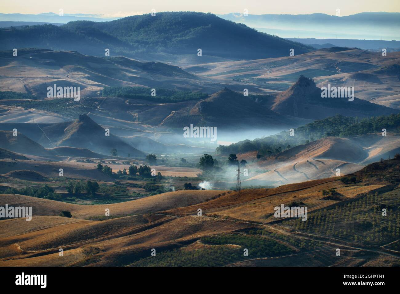 sicilian landscape of cultivated fields and hills in the morning mist ...