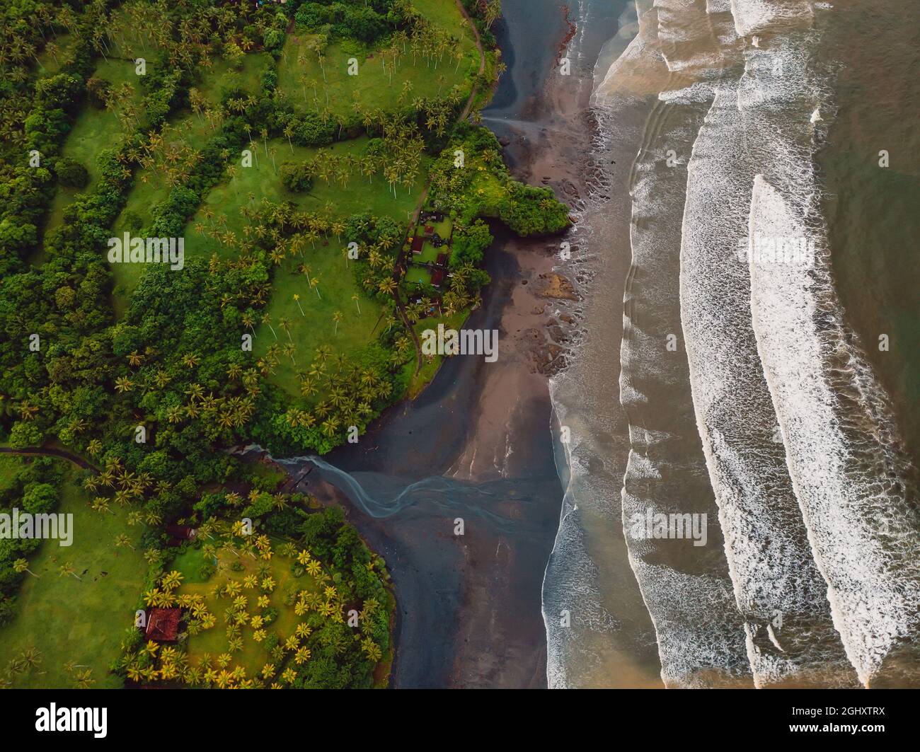 Aerial view of volcanic sand beach with river, ocean and waves in Balian, Bali Stock Photo