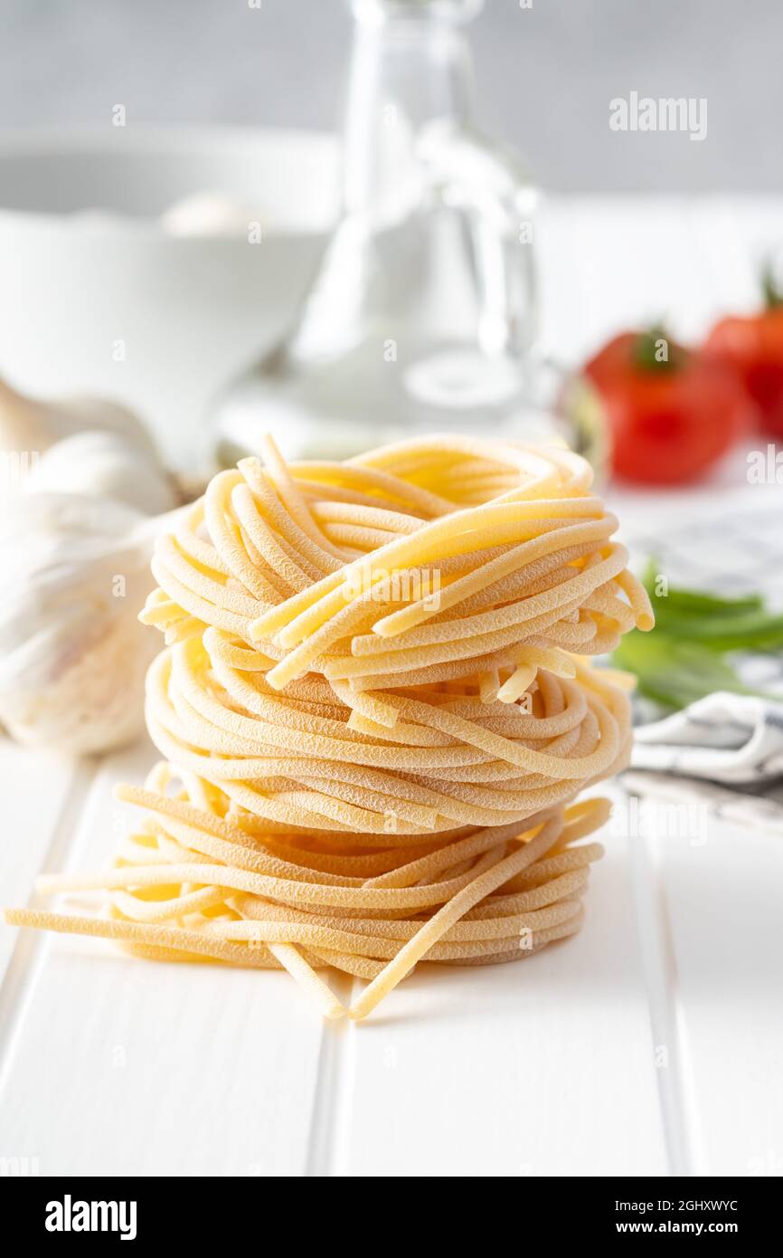 Italian pasta nest. Uncooked spaghetti nest on white table. Stock Photo