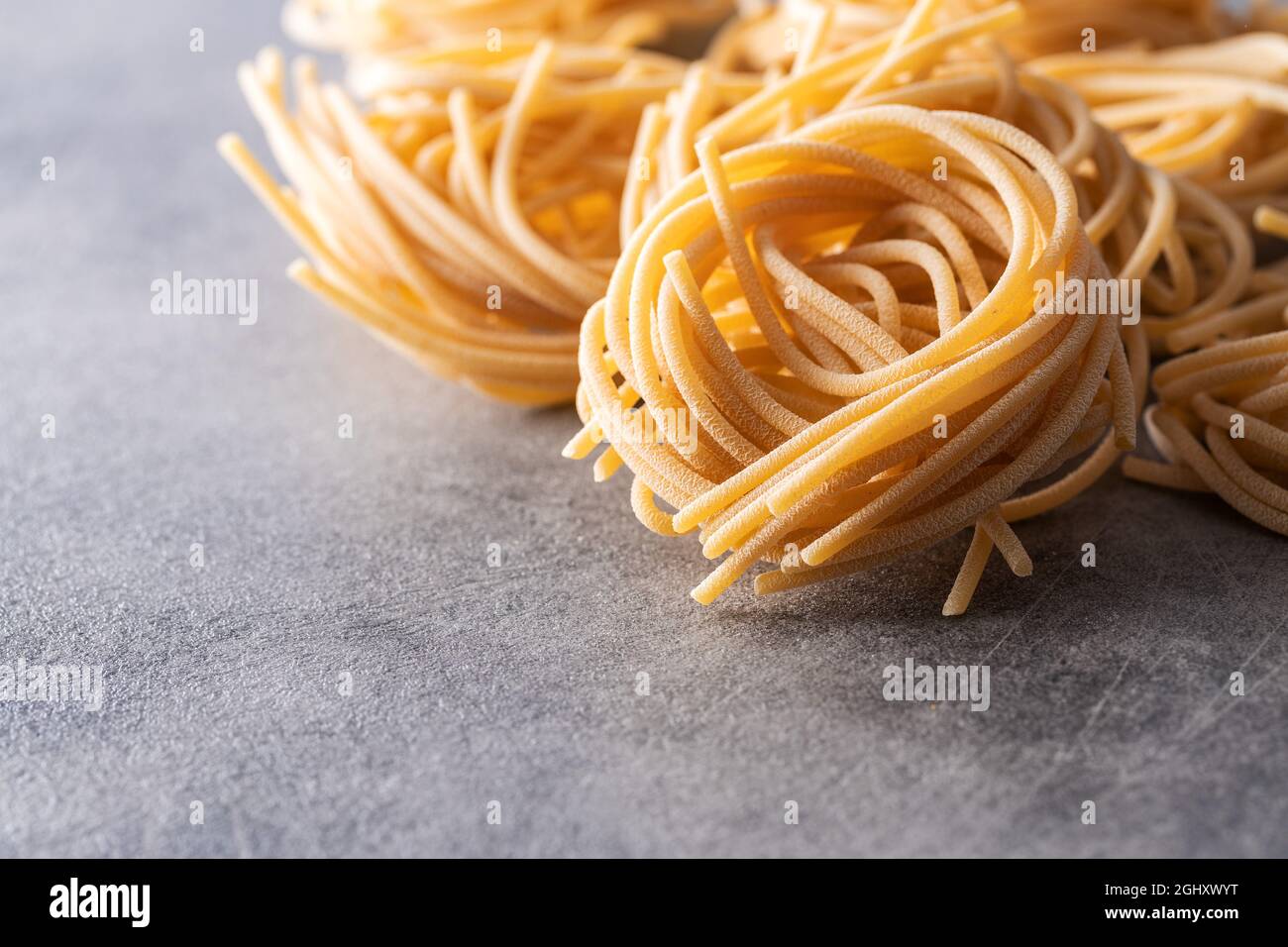 Italian pasta nest. Uncooked spaghetti nest on kitchen table. Stock Photo