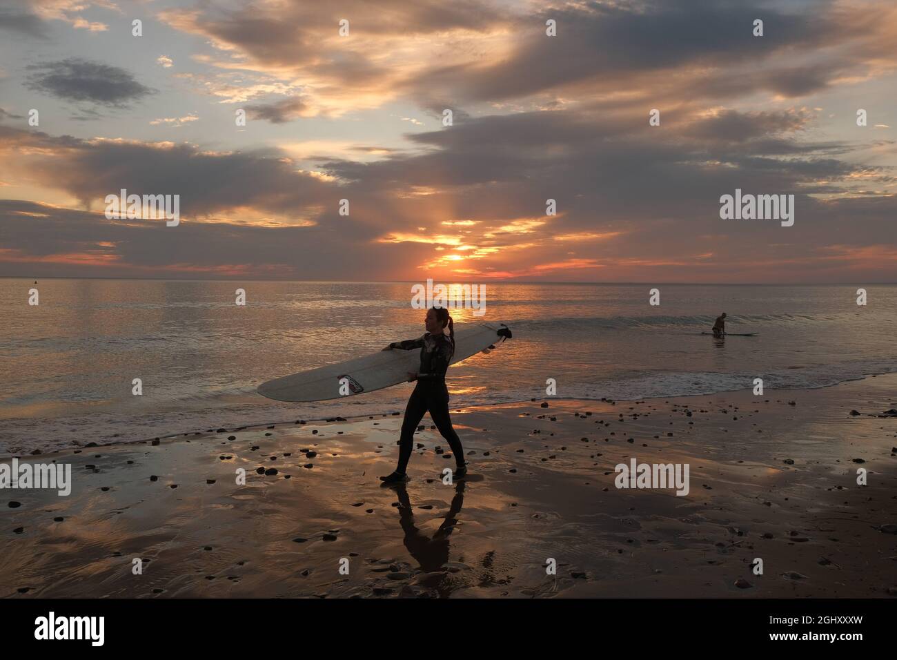 Gower, Swansea, UK. 7th September, 2021. UK Weather: a surfer leaves the water as the skies turn cloudy at Llangennith beach on the Gower peninsula. After a sunny and hot day, the south of the country is forecast to become showery with more unsettled conditions arriving from the west. Credit: Gareth Llewelyn/Alamy Live News Stock Photo