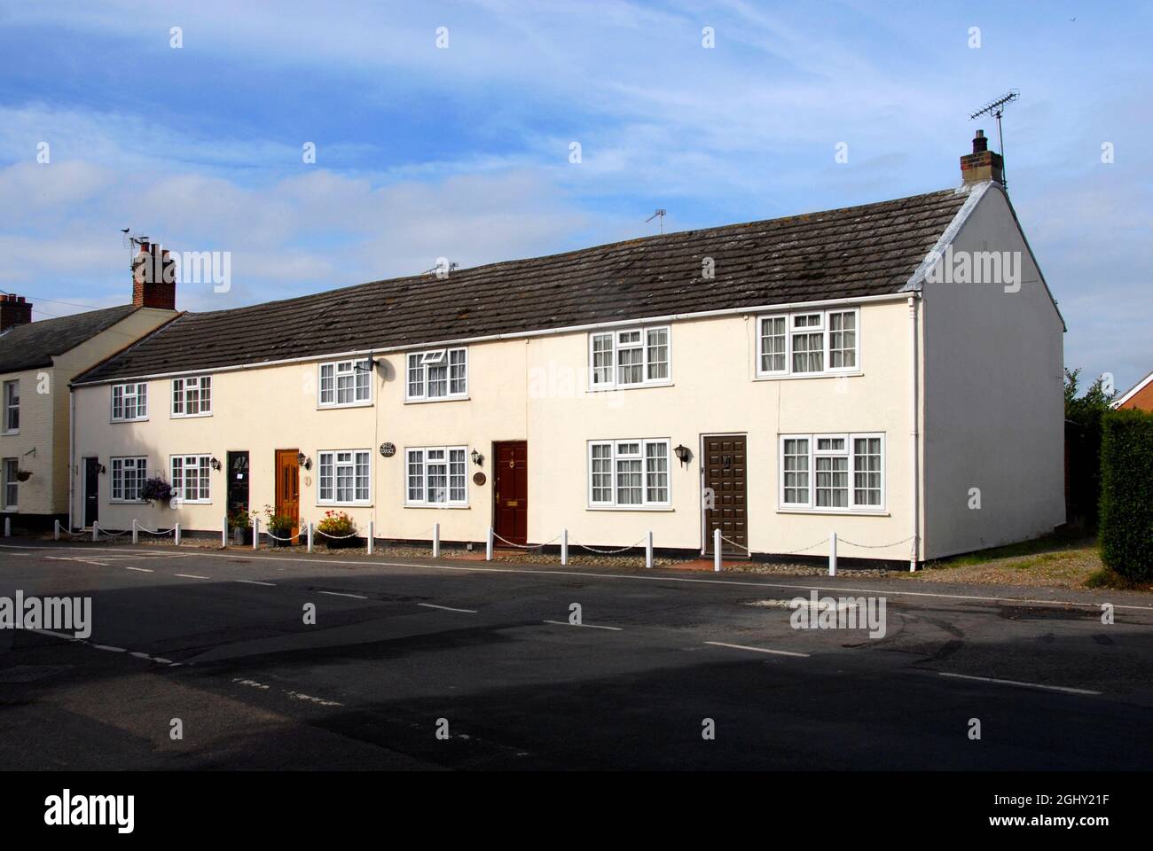 Row of smart terraced houses in the village of Ludham, Norfolk, England with four of them similar but the one on the right end larger than the others Stock Photo
