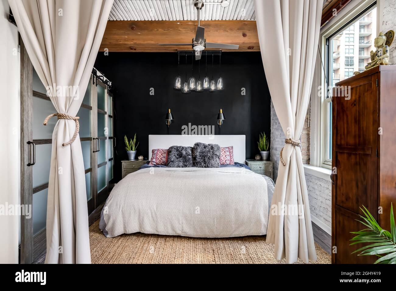 A bedroom in a loft condo with an exposed wood ceiling, glass sliding ...