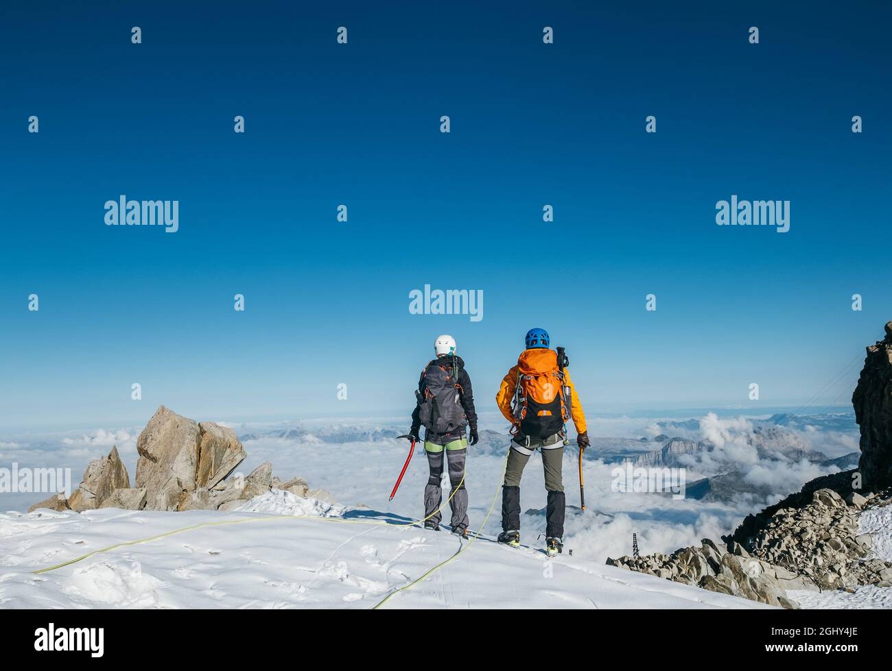 Couple connected team rope with climbing harness dressed mountaineering ...