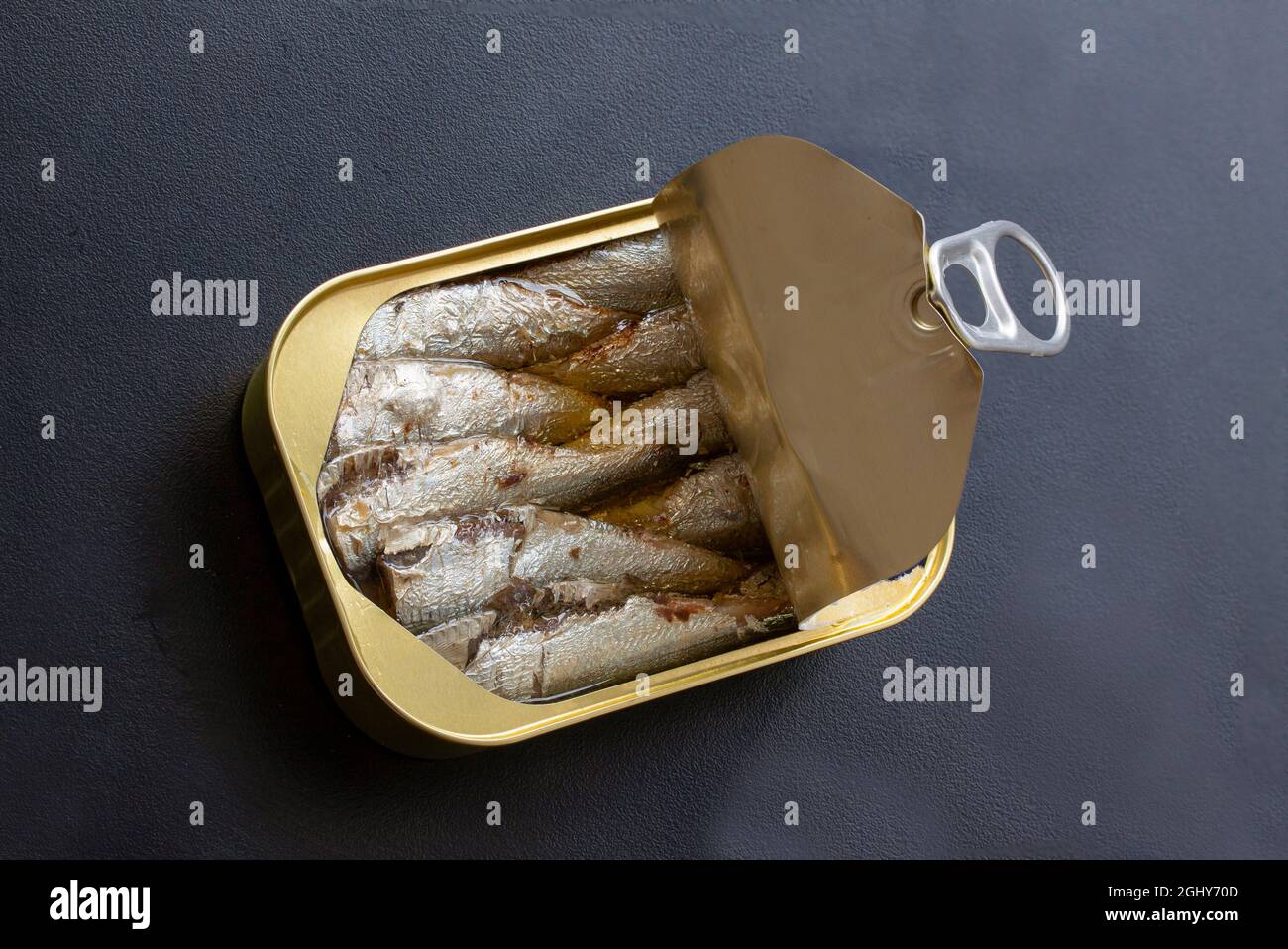 Open tin can of sardines with lid open and ring pull  on black background. Top view photo. Stock Photo