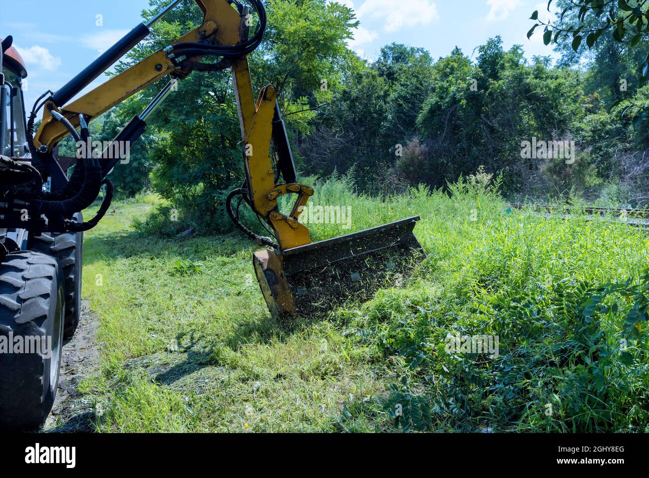 Road services of tractor machine with grass cutter mowing lawn along road Stock Photo