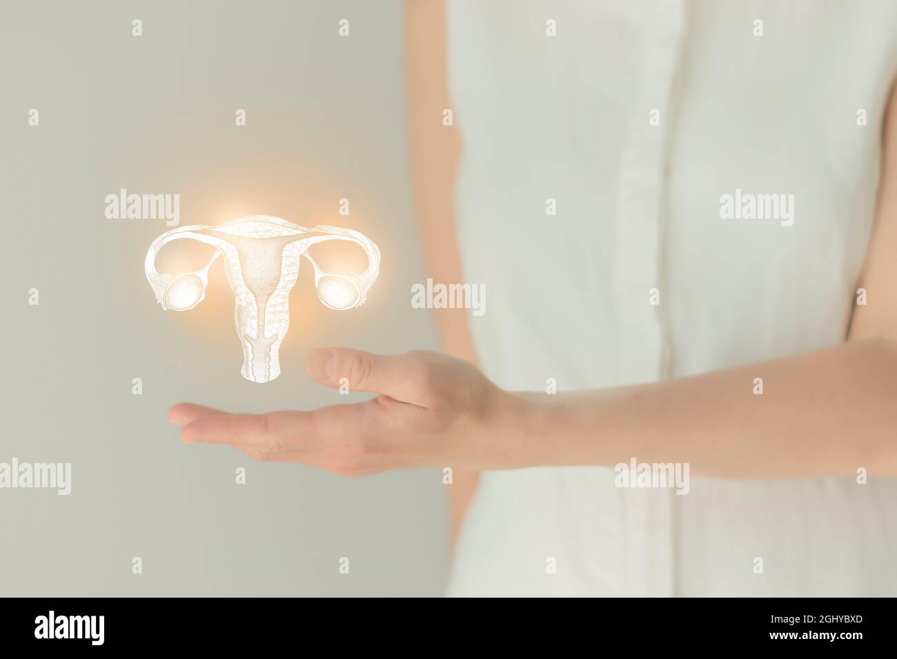Unrecognizable female patient in white clothes, highlighted handrawn uterus in hands. Human reproductive system issues concept. Stock Photo