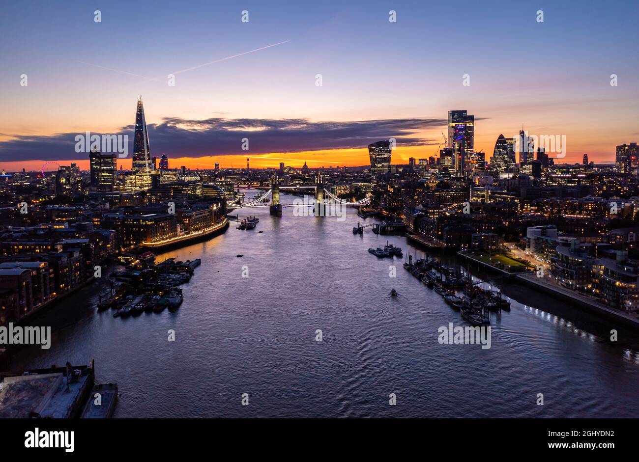Aerial view of the famous Tower Bridge over ocean surrounded with buildings and skyscrapers under a cloudy twilight and dusk orange morning sky Stock Photo