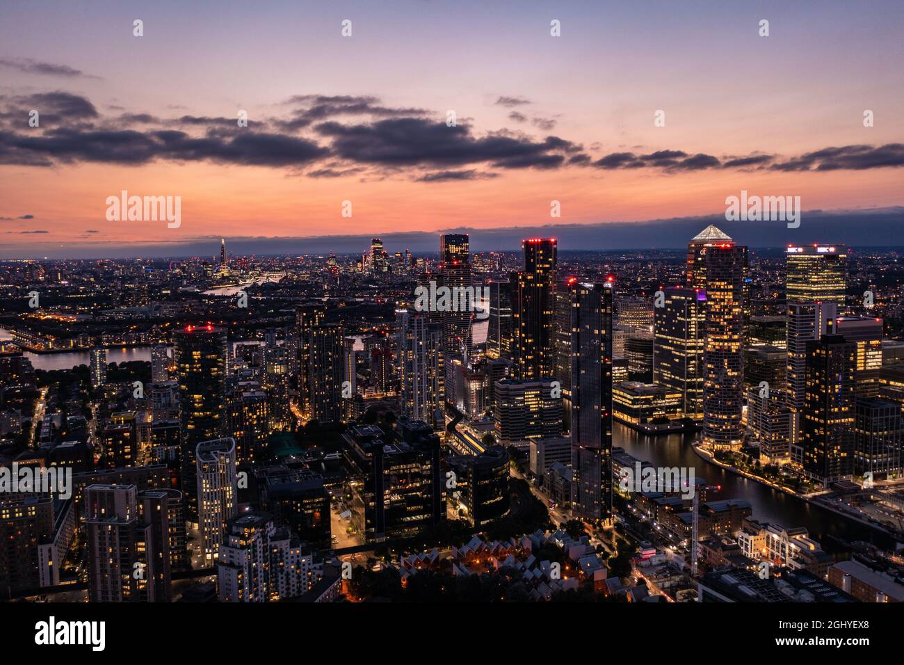 Panoramic aerial skyline view of east London at night with skyscrapers of Canary Wharf and beautiful colorful sky at background Stock Photo