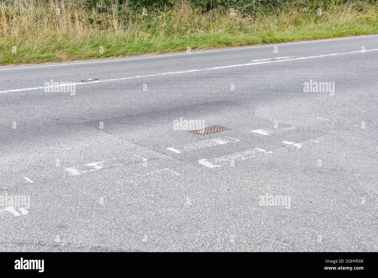 Poorly maintained white road markings at the T-junction of a country A road. For road safety, fading away metaphor, difficult to see. Stock Photo