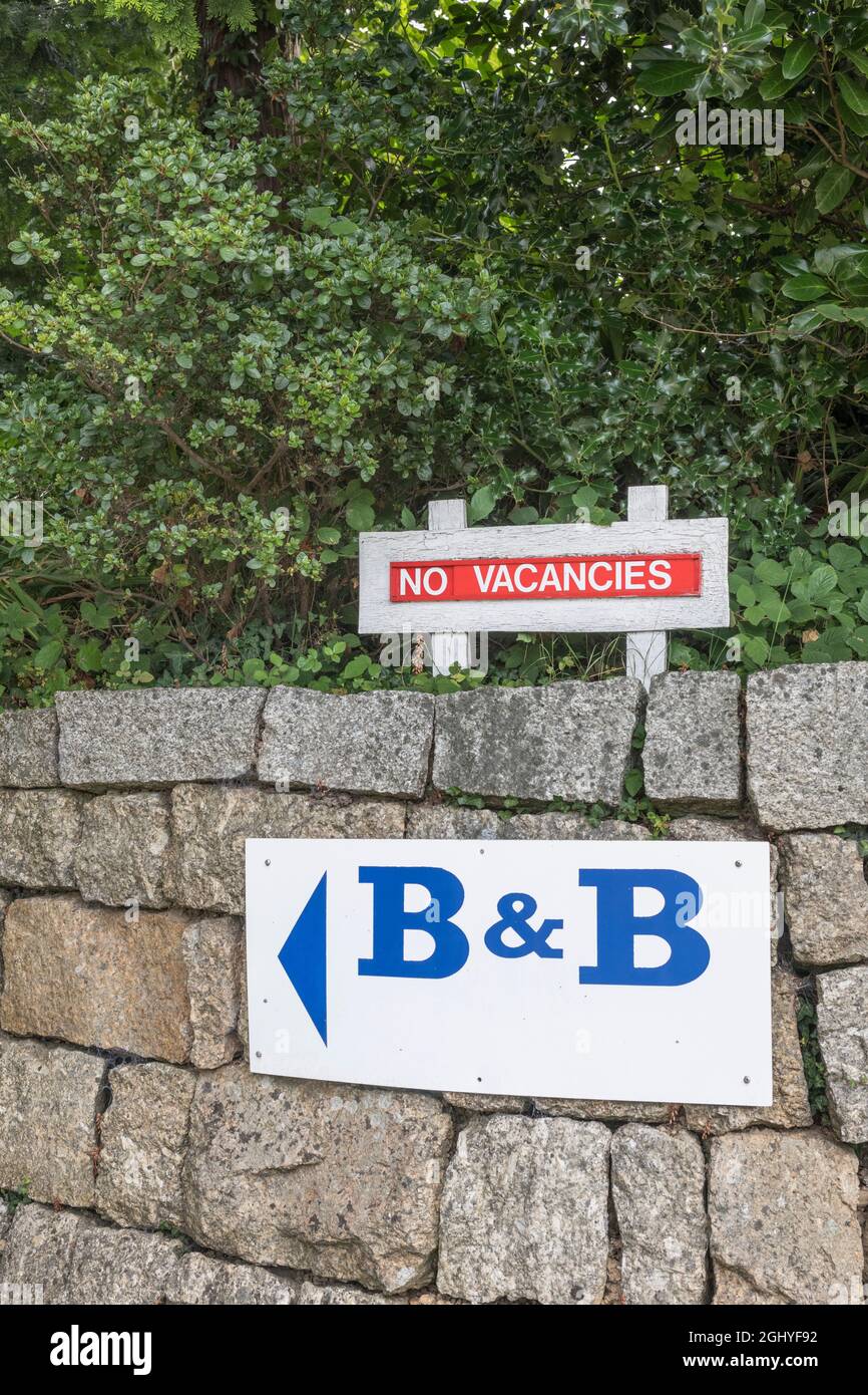 Red 'No Vacancy' sign beside a Cornwall B&B sign in the town of Lostwithiel. For UK staycations, Cornwall hospitality business, Covid holidays Stock Photo