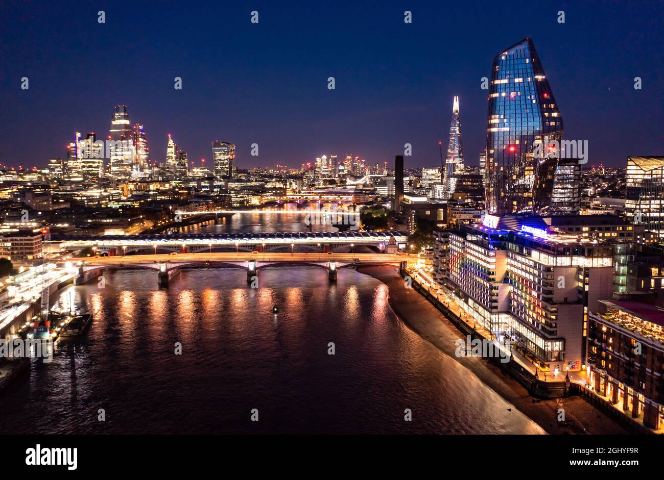 Night view of the beautiful London city with urban architectures bridge at distance with skyscrapers and small buildings around ocean water Stock Photo