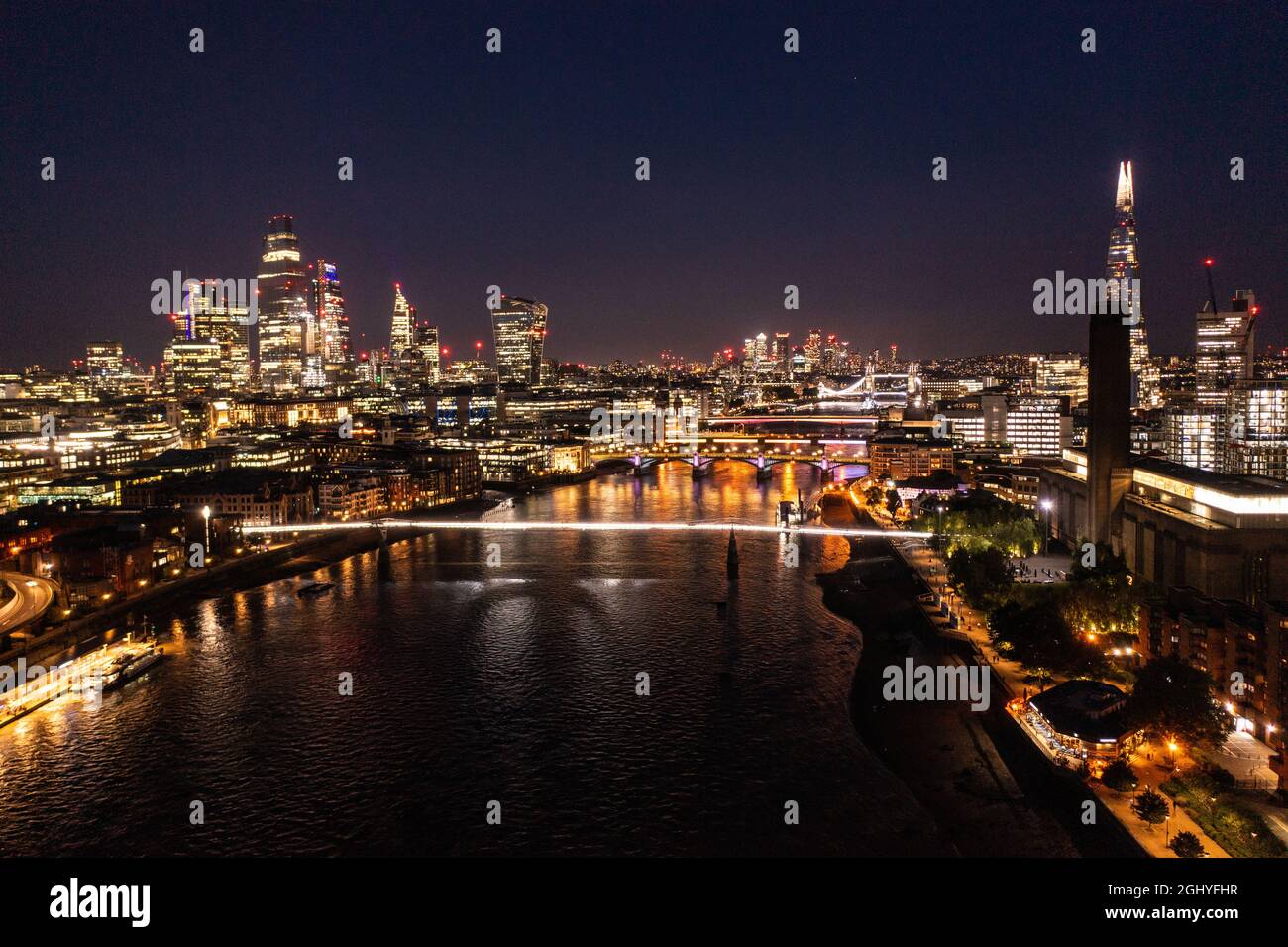 Night view of the beautiful London city with urban architectures and Tower Bridge at distance with skyscrapers and ocean water Stock Photo