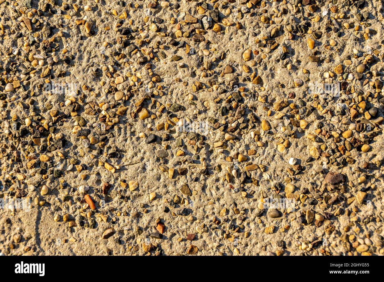 textured background created by a surface of sand covered with a non-uniform layer of fine gravel Stock Photo
