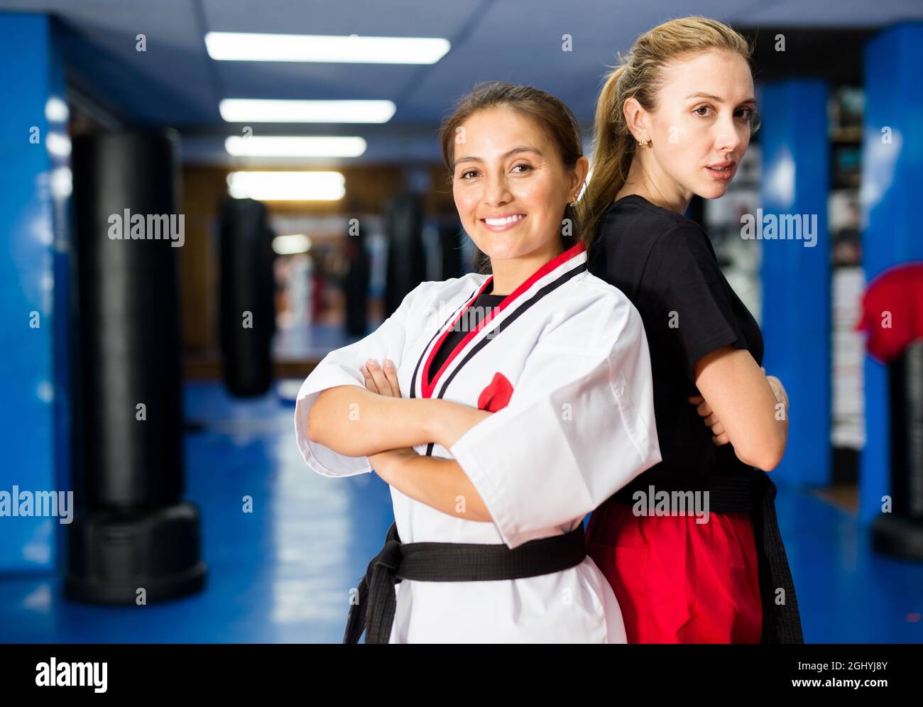Two confident female martial arts fighters with arms crossed in gym